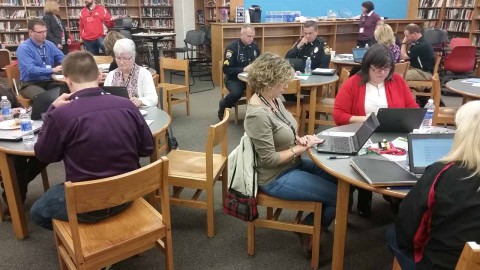Groups of people at tables taking a survey on their laptops